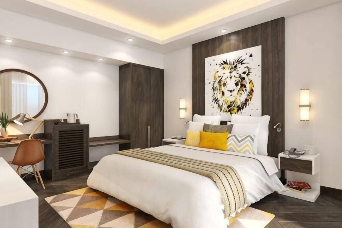 A modern hotel bedroom with a large bed, bedside tables, a desk, and a wardrobe.