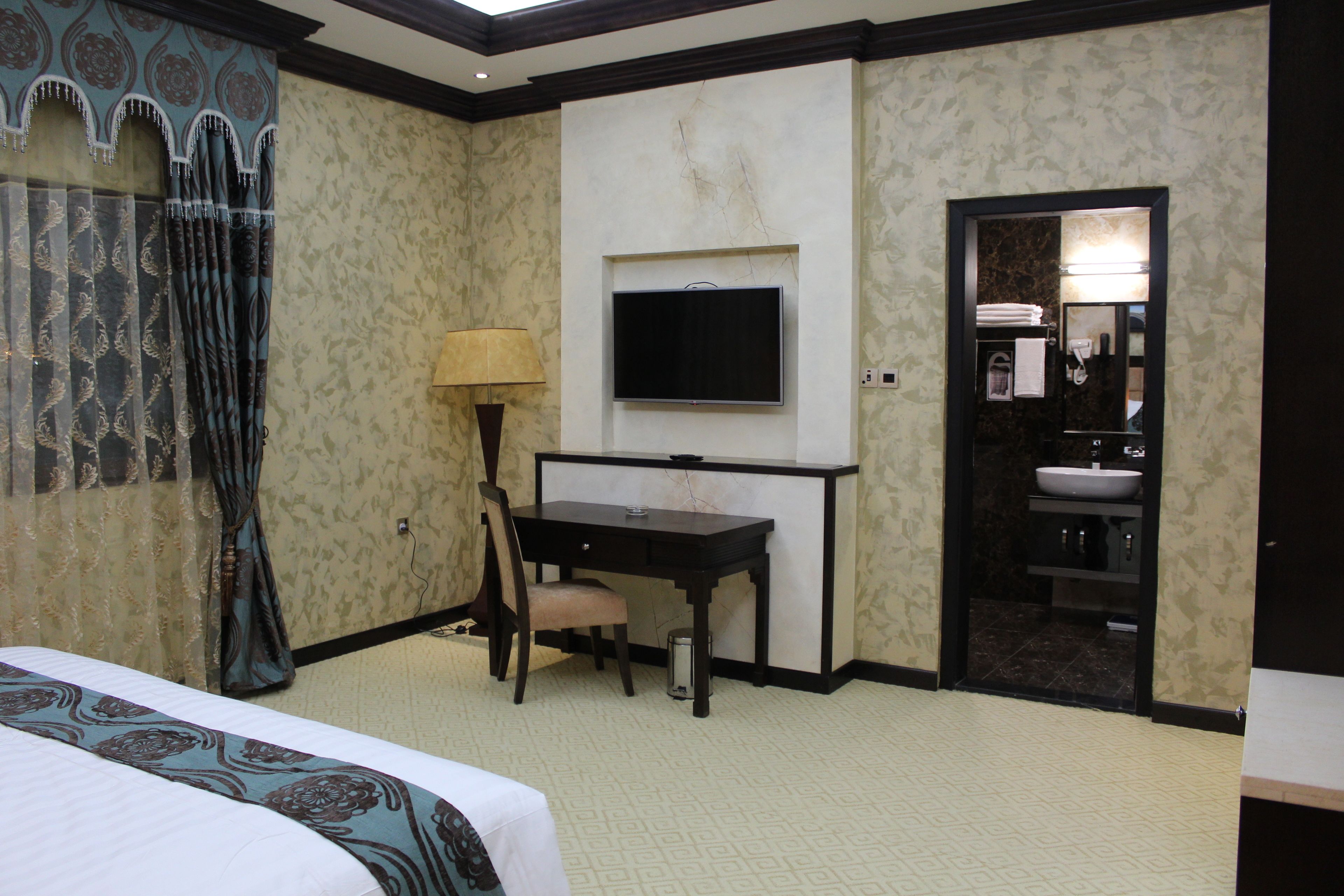 A hotel room with a bed, desk, chair, TV, and bathroom.