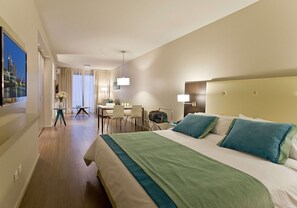 Ett hotellrum med en stor säng, ett skrivbord, en stol och en tv.