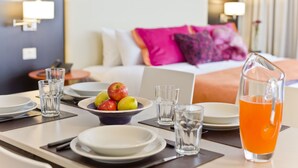 A hotel room with a neatly arranged breakfast table, a laptop, and a pitcher of orange juice.