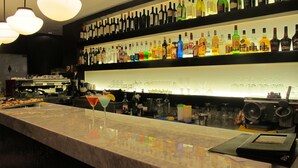 A bar area with a marble countertop, shelves of various liquor bottles, and a martini glass.