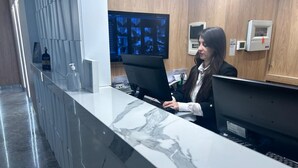 A reception desk with a marble top, two computer monitors, and a wooden wall in the background.