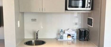 A compact kitchenette with a sink, microwave, and small refrigerator.
