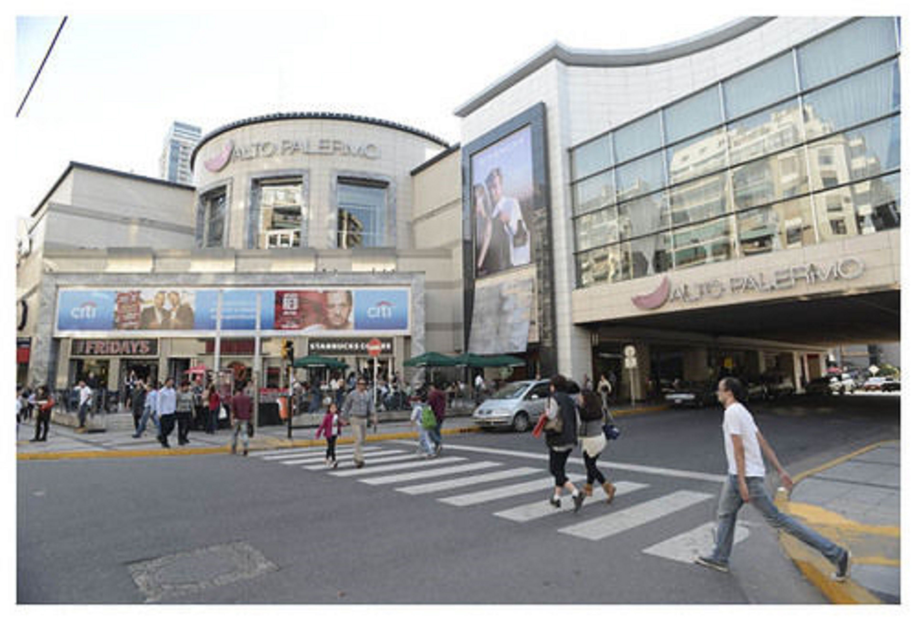 A busy street with a large building featuring a prominent sign for Alto Palladio.