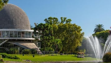 A modern building with a spherical structure, surrounded by lush greenery and a fountain.