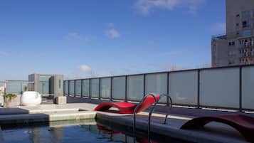 A rooftop pool area with modern seating and a glass barrier.