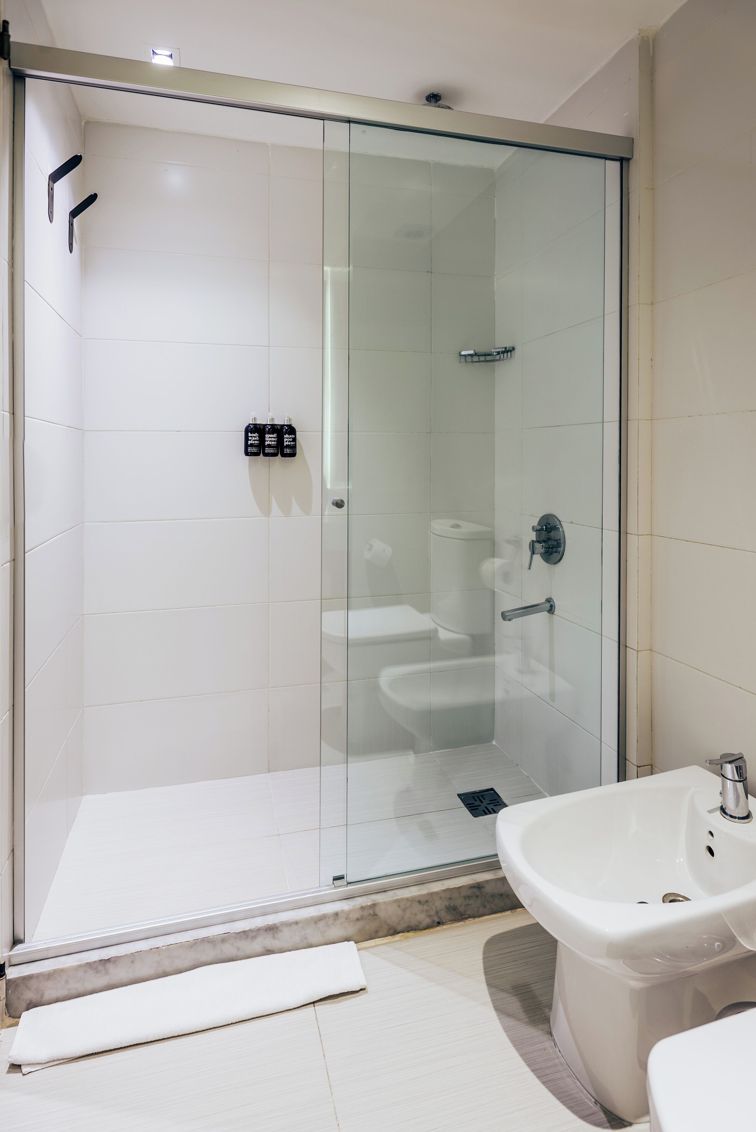 A modern bathroom with a glass-enclosed shower, a white sink, and a toilet.