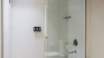 A modern bathroom with a glass-enclosed shower, a white sink, and a toilet.