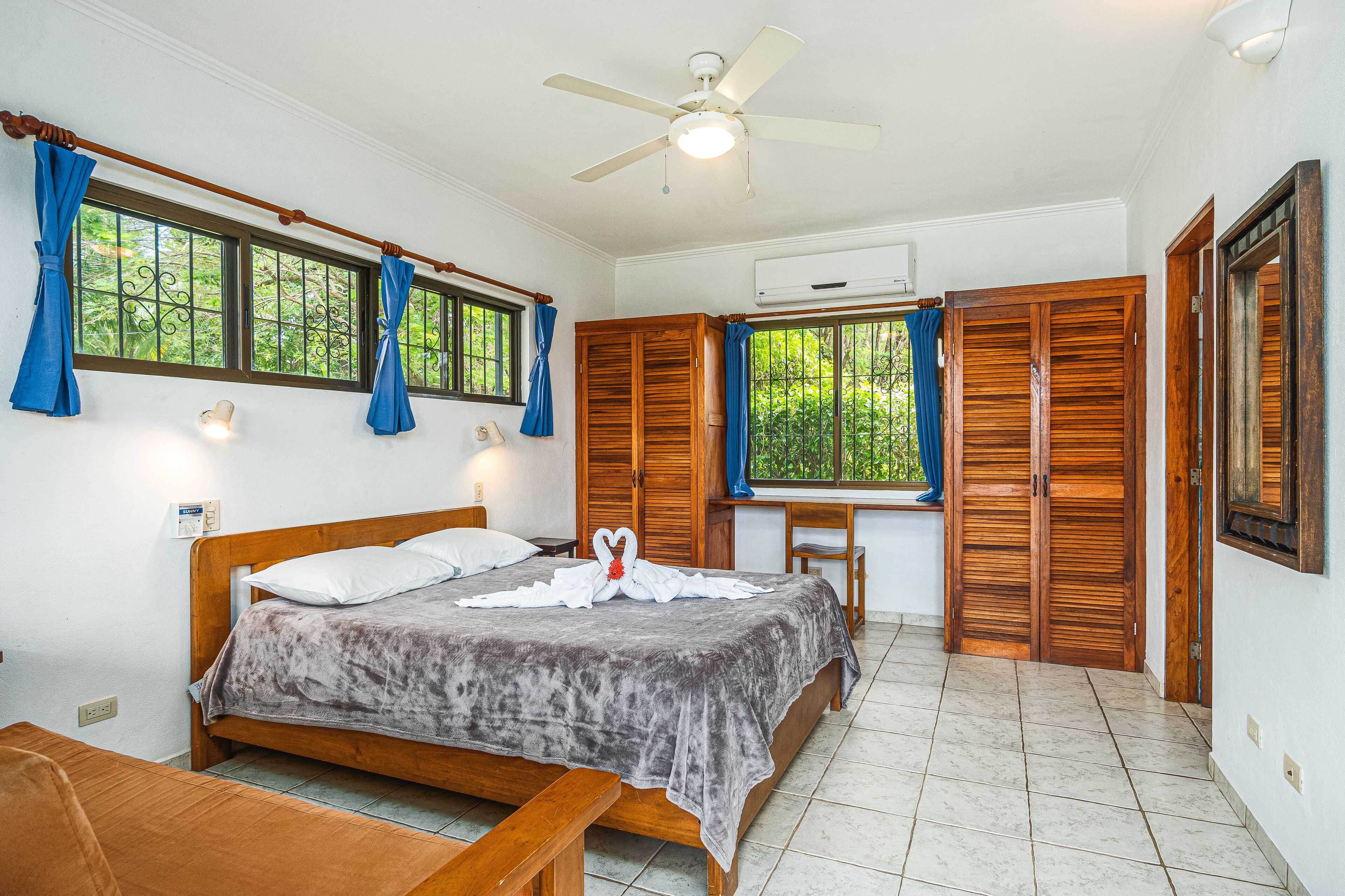 A bedroom with a bed, wooden wardrobe, and a desk with a chair.