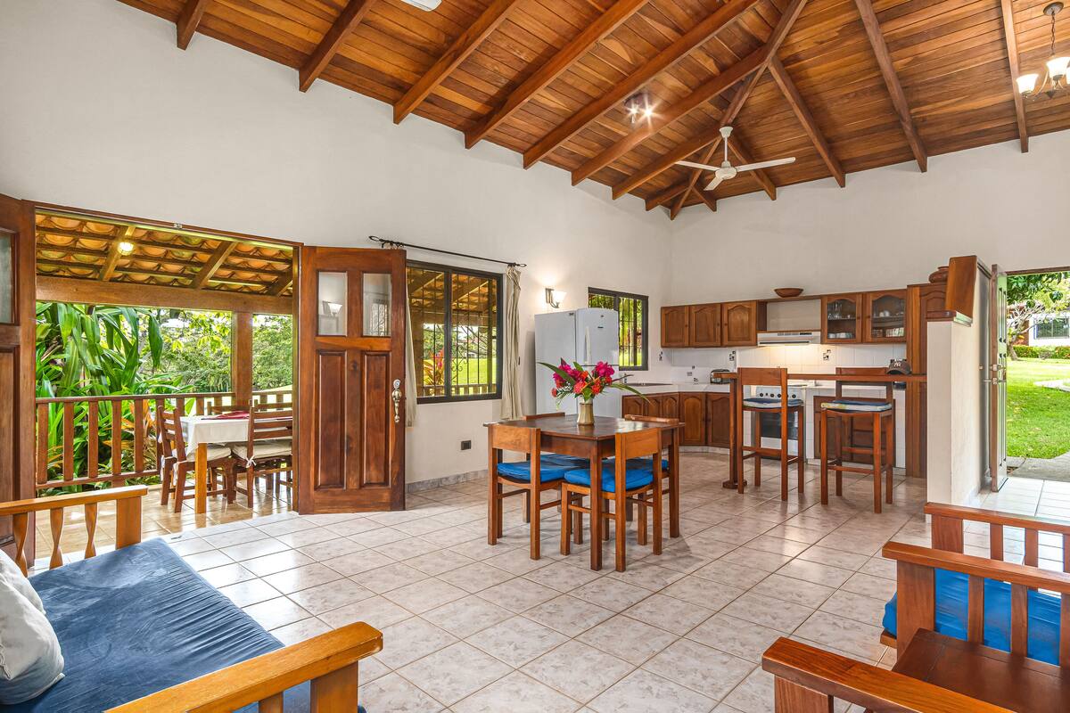Una cocina amplia con armarios de madera, una zona de comedor con mesa y sillas, y un balcón con barandilla de madera.