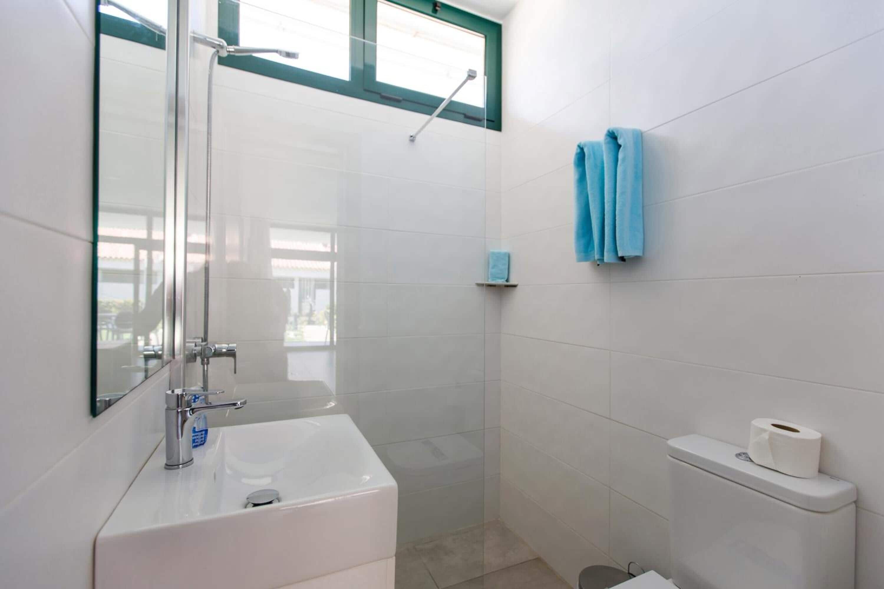 A modern bathroom with a glass-enclosed shower, a white sink, and a toilet.