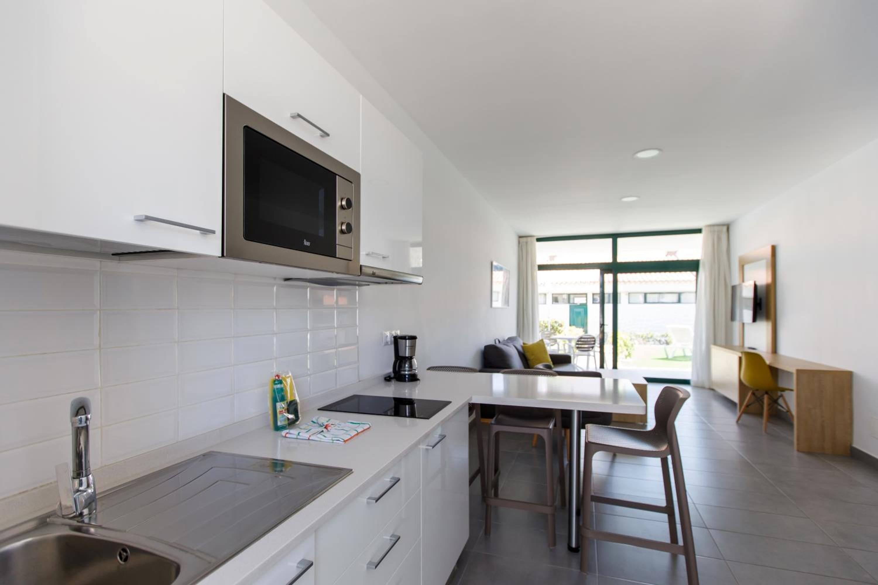 A modern kitchen with white cabinets, a stainless steel sink, and a built-in microwave.
