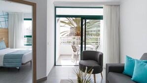 A modern hotel room with a balcony, a bed, a sofa, and a chair.