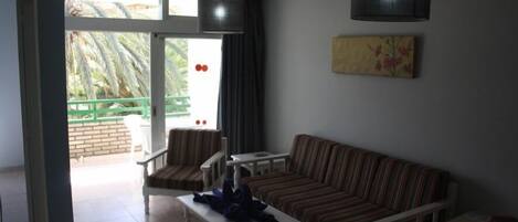 Een woonkamer met een bank, fauteuils, een salontafel en een schilderij aan de muur.