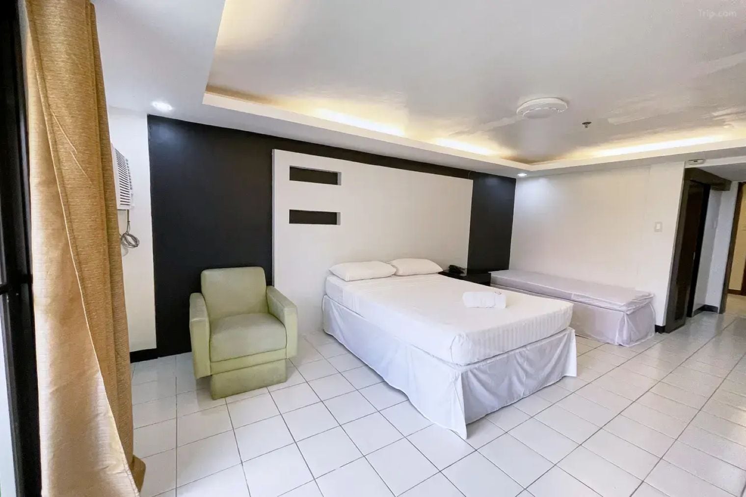 Moderni hotellihuone, jossa on sänky, tuoli ja penkki.