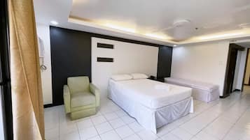Moderni hotellihuone, jossa on sänky, tuoli ja penkki.