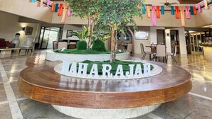 A lobby with a circular wooden table, a central tree, and the name 'MAHARAJAD' on the table. - Maharajah Hotel Angeles City (Angeles City)