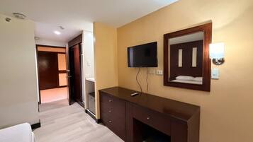 A hotel room with a bed, a desk, a television, and a mirror.