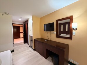 A hotel room with a bed, a desk, a television, and a mirror. - Palette Maharajah Hotel Angeles City (Angeles City)