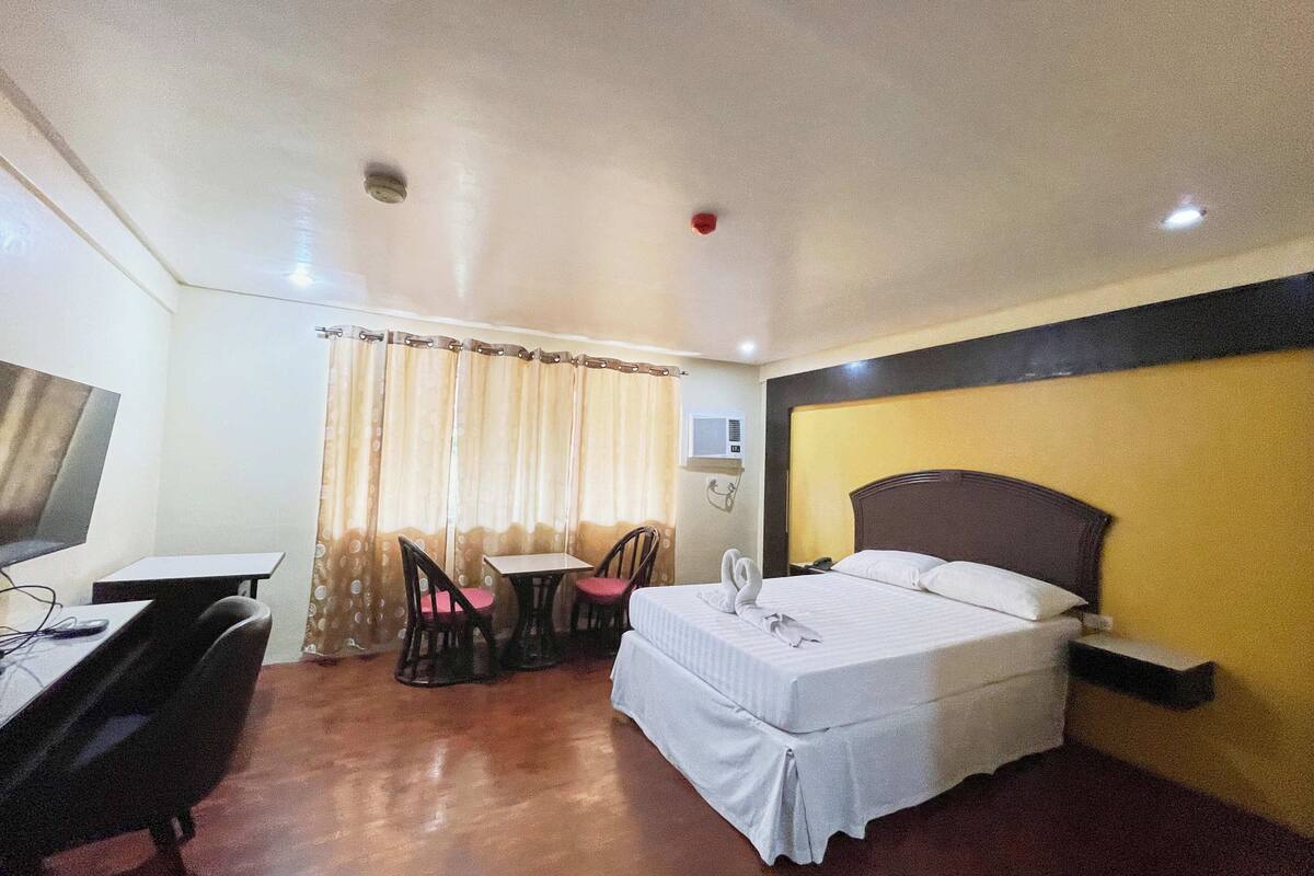 Ein Hotelzimmer mit Bett, Schreibtisch, Stuhl und einem kleinen Tisch.
