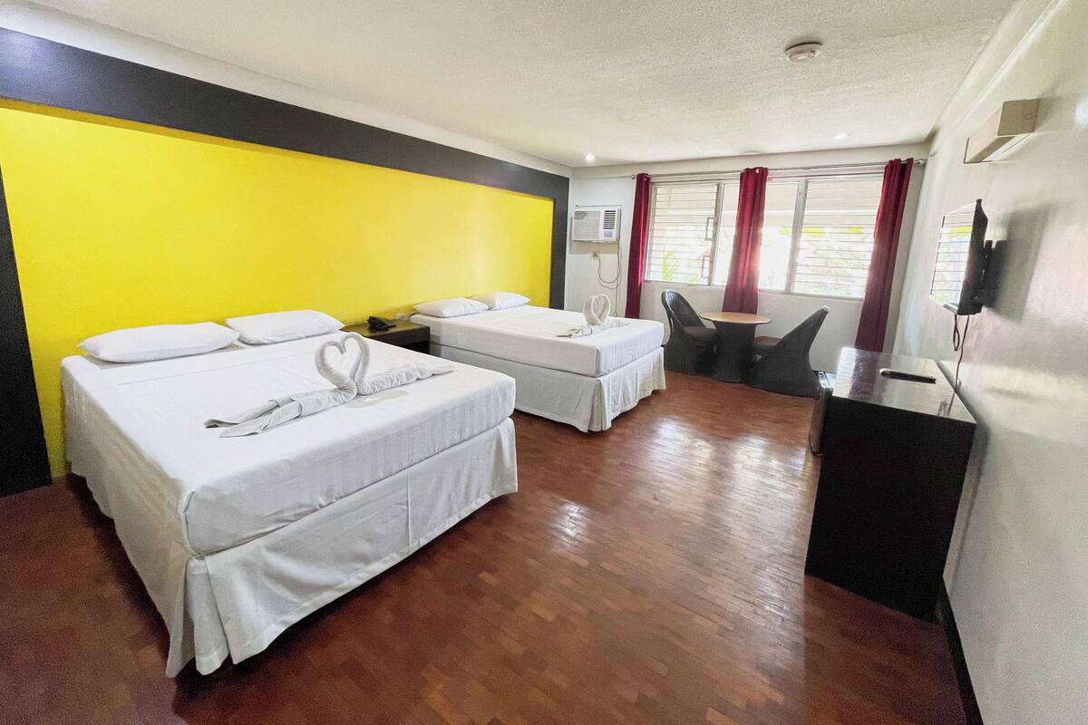 Ein Hotelzimmer mit zwei Betten, einem Schreibtisch, einem Stuhl und einem Fernseher.