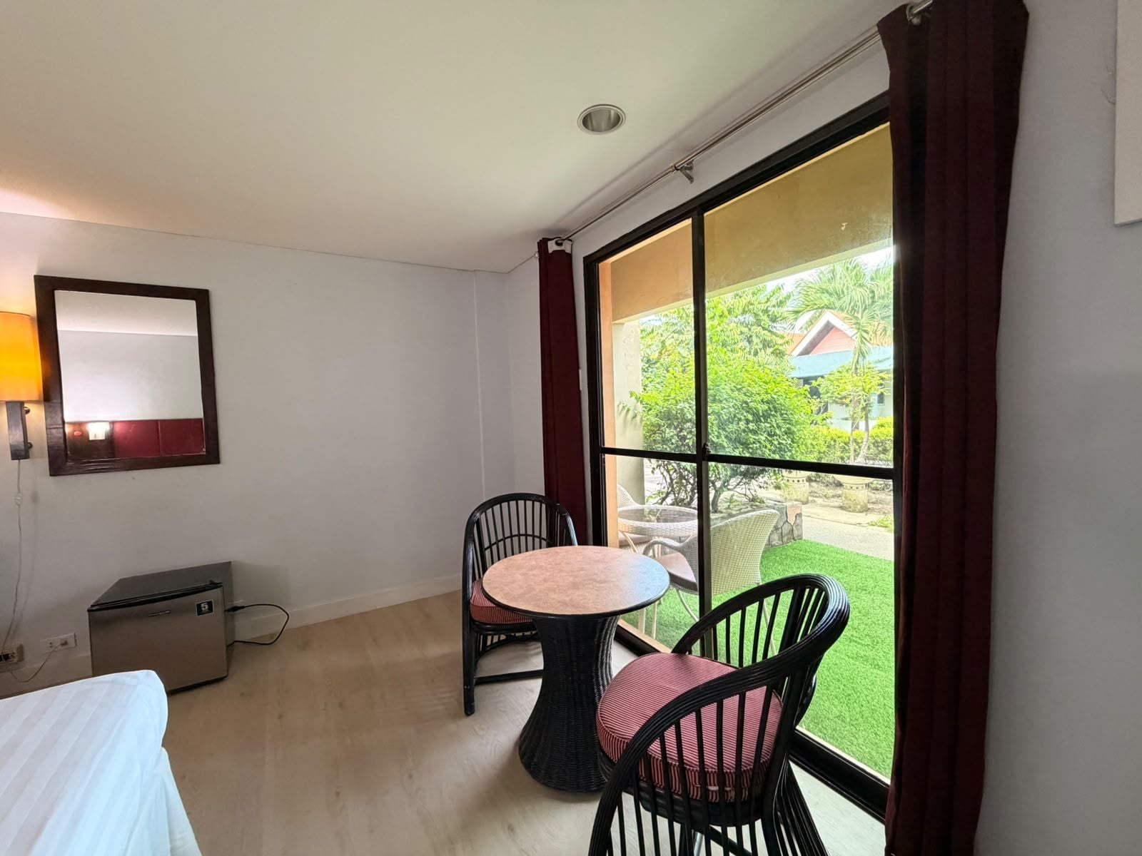Habitación de hotel con una cama, un escritorio pequeño, una silla, una mesa redonda y un ventanal con vistas al exterior.