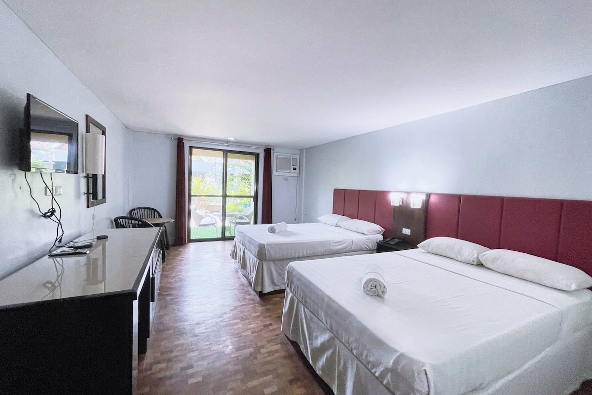 Ein Hotelzimmer mit zwei Betten, einem Schreibtisch, einem Stuhl und einem Fernseher.