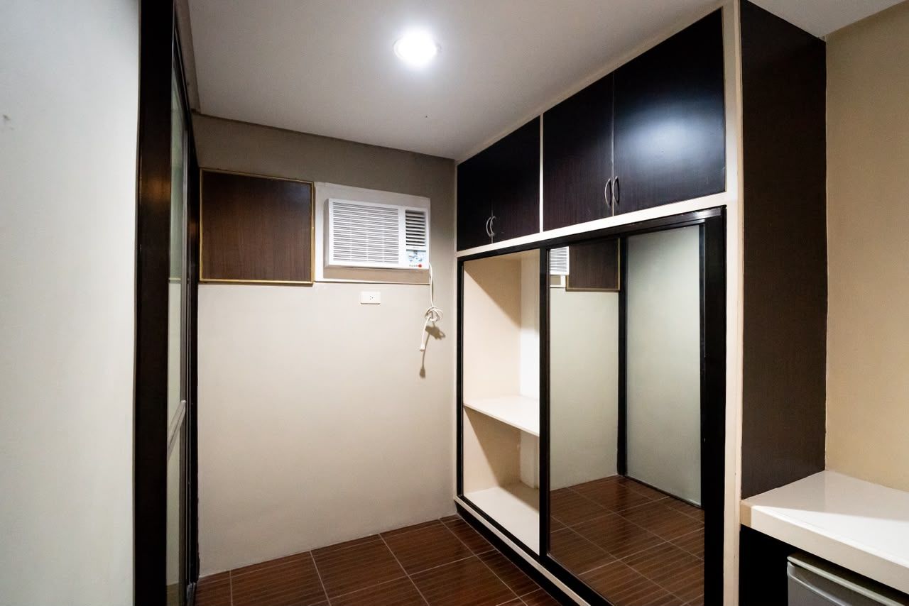 Quarto com armário, janela com persianas e piso ladrilhado.