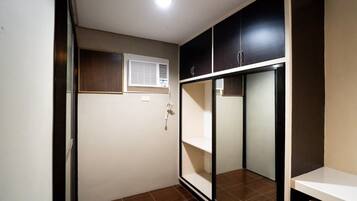 Quarto com armário, janela com persianas e piso ladrilhado.
