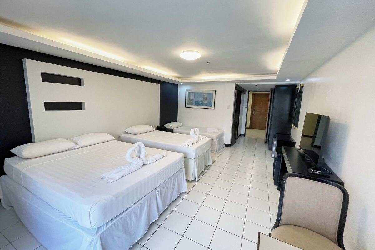 Ein Hotelzimmer mit zwei Betten, einem Schreibtisch, einem Stuhl und einem Fernseher.