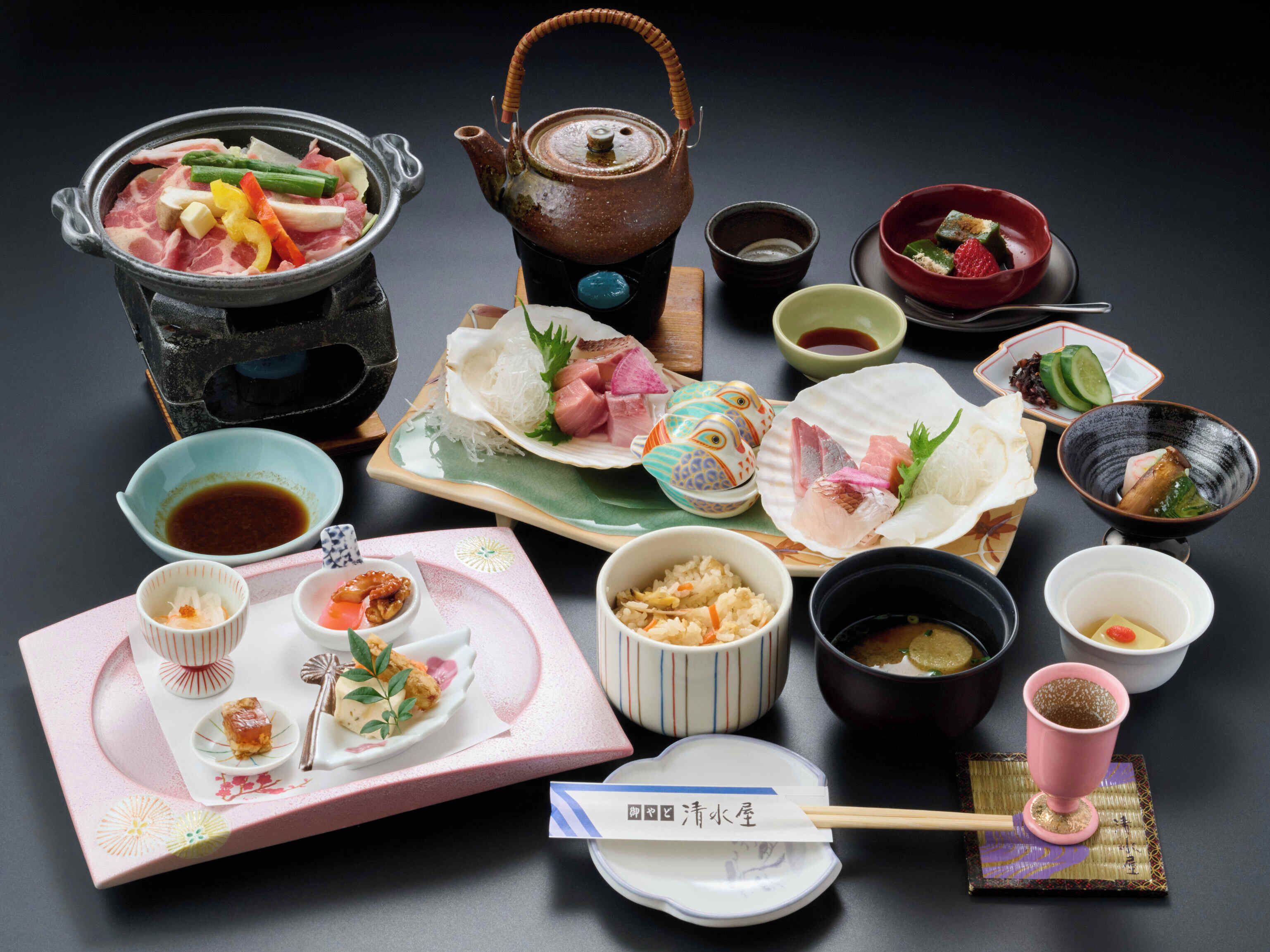 Una comida tradicional japonesa con varios platos, una tetera y palillos.