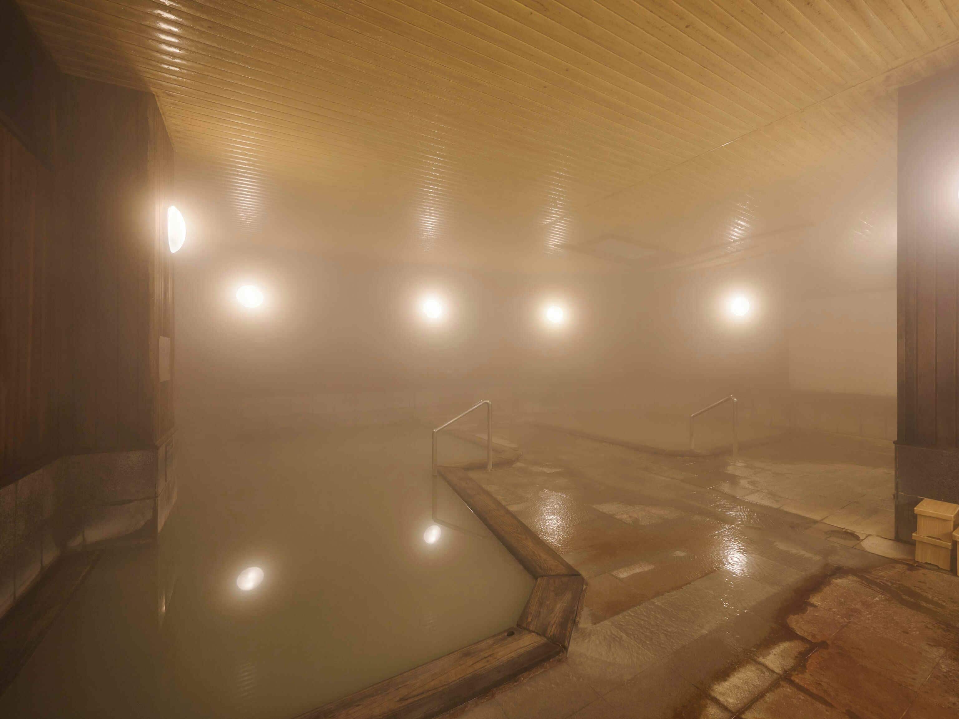 A steam room with a wooden ceiling, a central pool, and multiple light fixtures.
