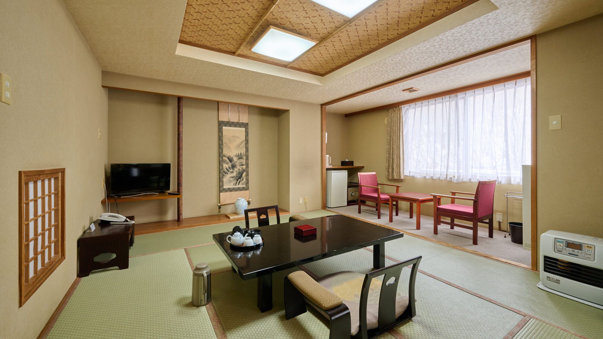 A traditional Japanese-style room with tatami flooring, a low table, and a television.