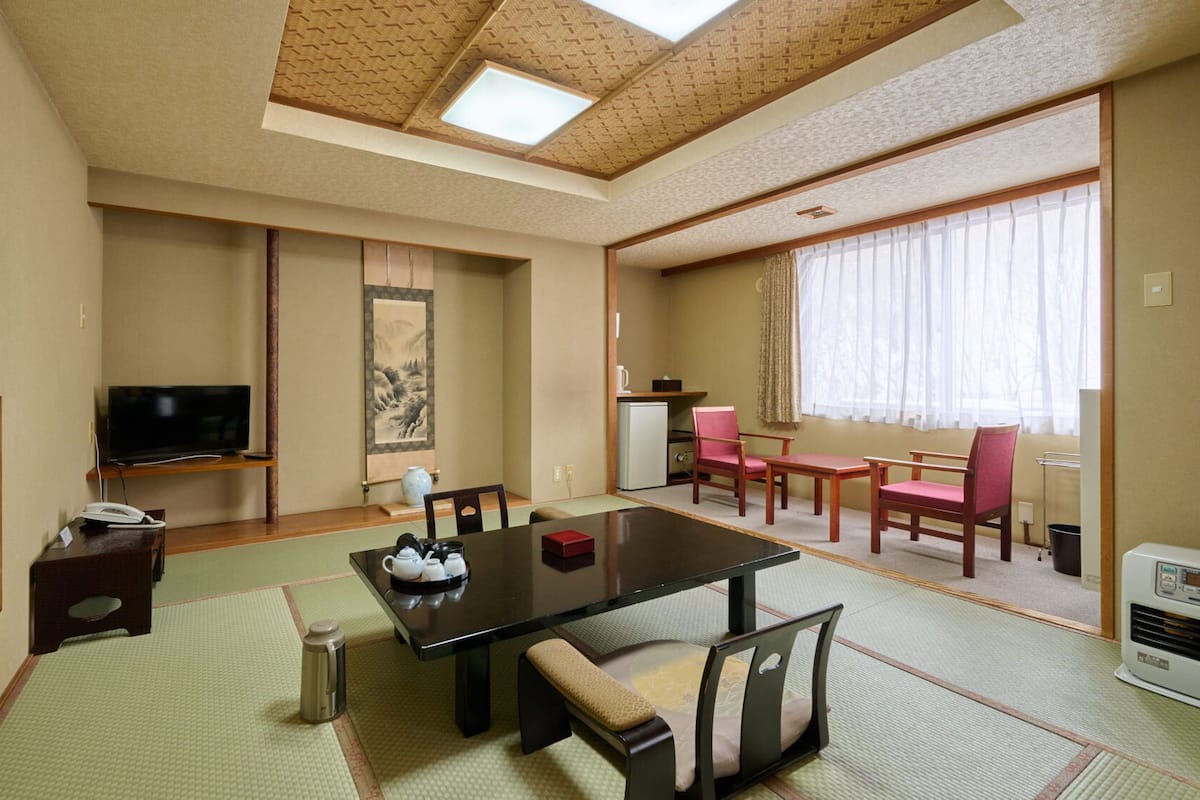 Una habitación tradicional japonesa con suelo de tatami, una mesa baja y un televisor.