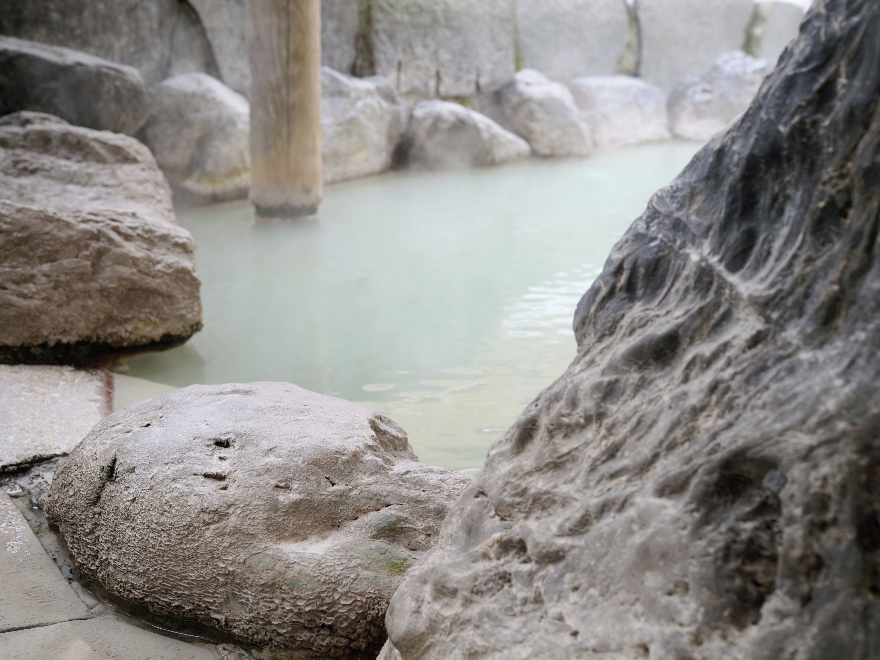 Una poza rocosa con piedras grandes y una superficie de agua tranquila.