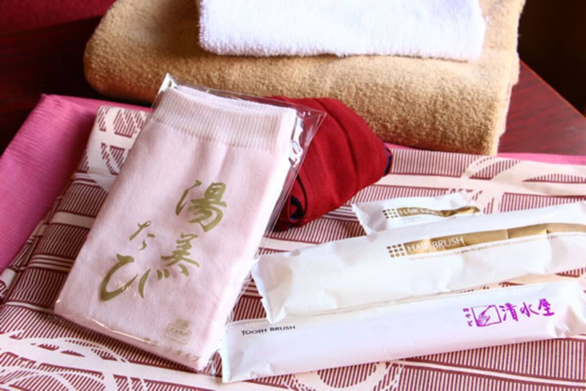 A towel, a red cloth, and a white package with Japanese text on a patterned surface.