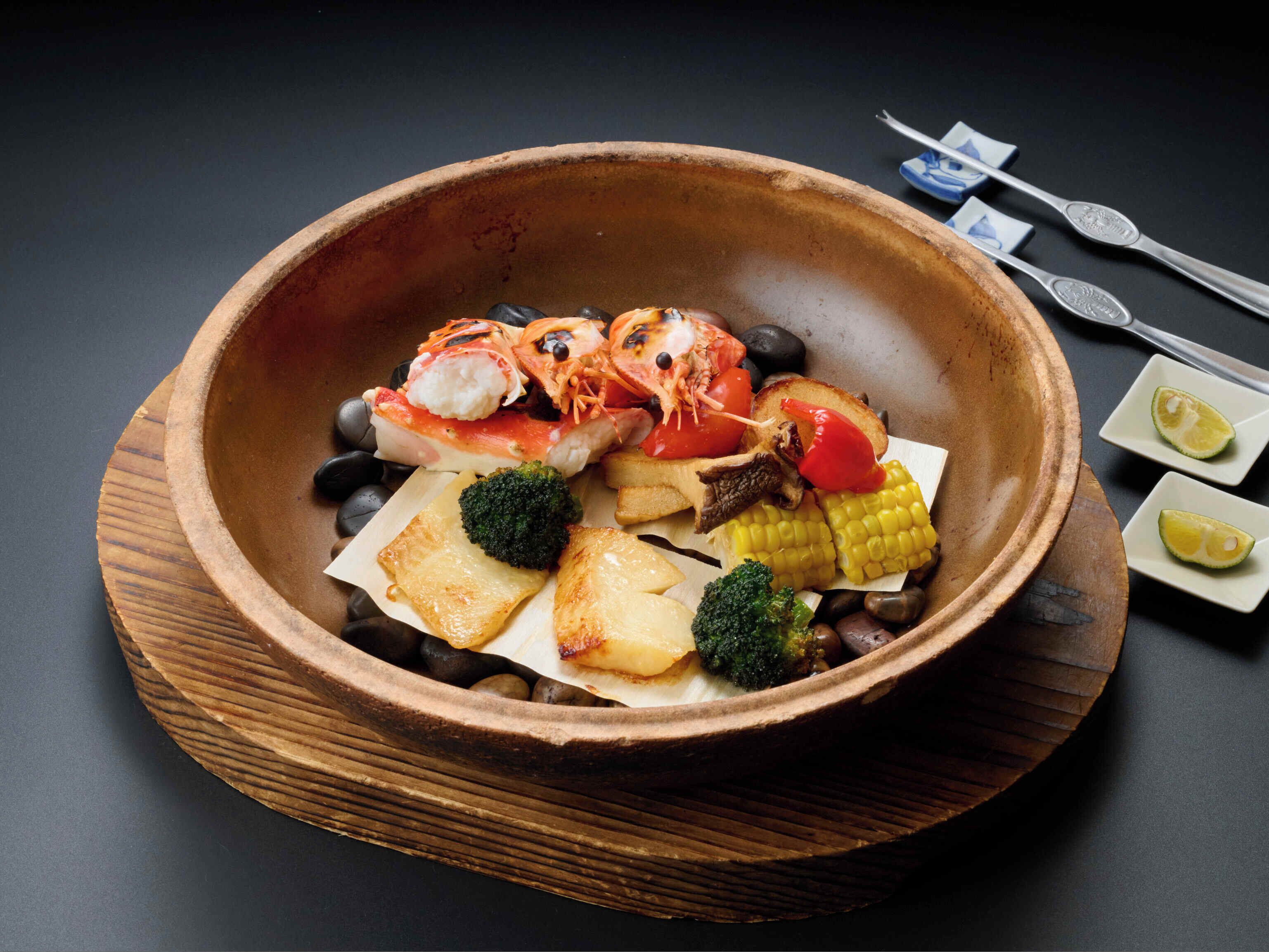 A wooden bowl containing various seafood and vegetables.