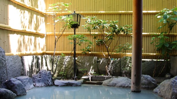 A traditional Japanese garden with a wooden structure, bamboo fence, and a koi pond. - Oyado Kiyomizuya (Noboribetsu)