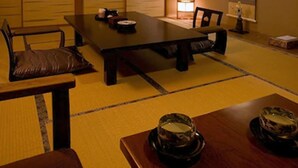 A traditional Japanese-style room with tatami flooring, a low table with cushions, a long dining table, and a painting on the wall. - Oyado Kiyomizuya (Noboribetsu)