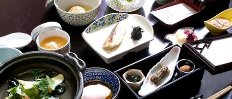 A variety of Japanese dishes and utensils on a table, including a bowl of soup, a plate of sushi, and a bowl of rice.