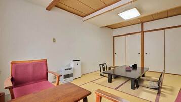 A traditional Japanese room with tatami flooring, a low table, a chair, a heater, and a sliding door.