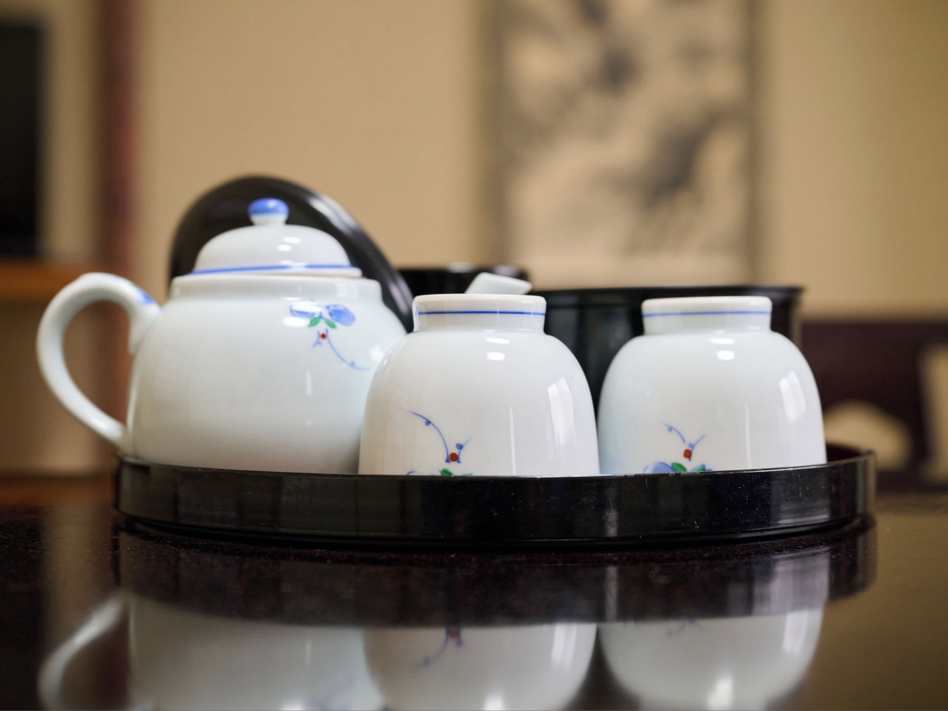 A set of white ceramic teapots with floral designs on a reflective surface.