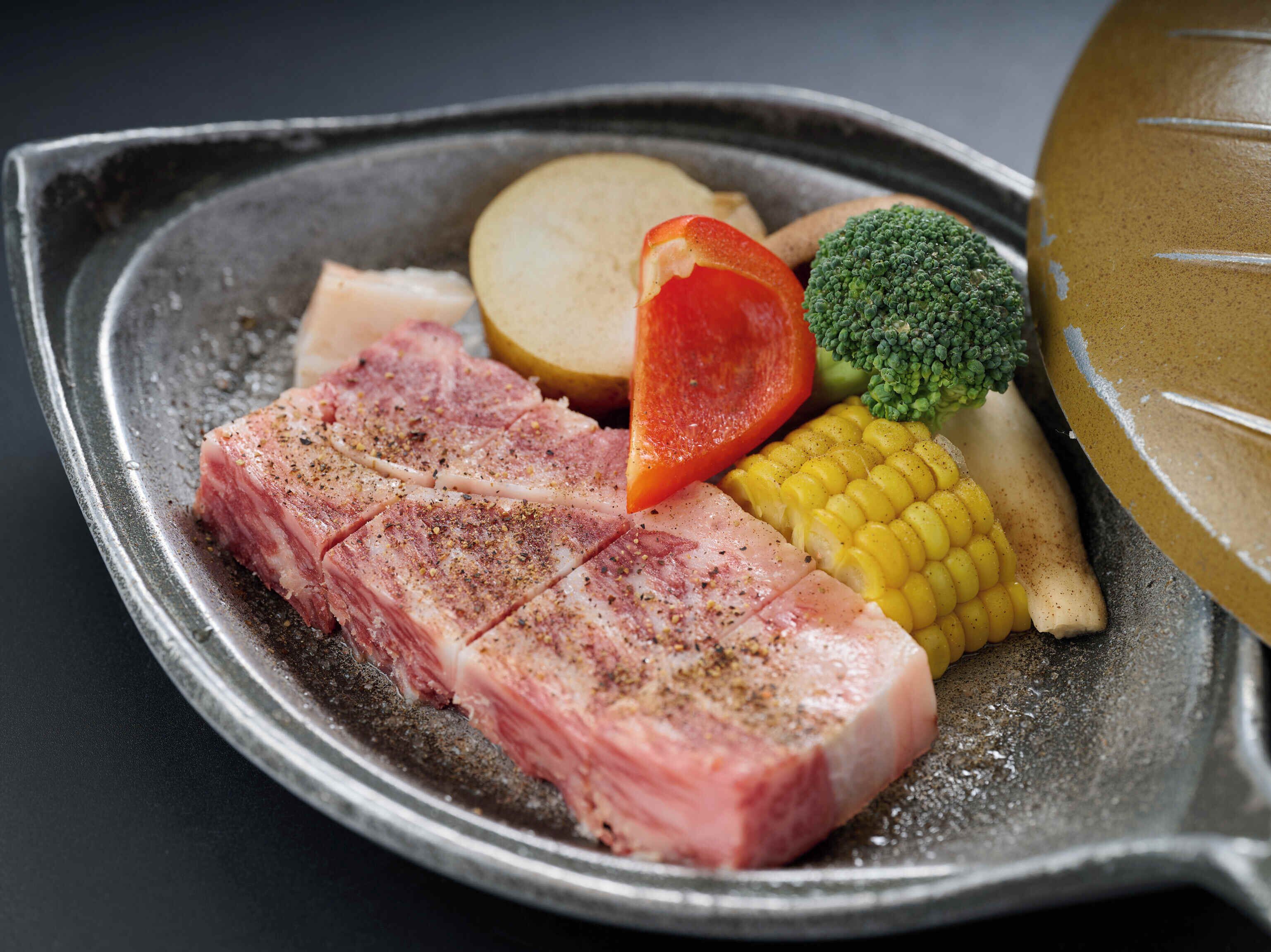 A plate with sliced meat, a tomato, corn, broccoli, and a potato.