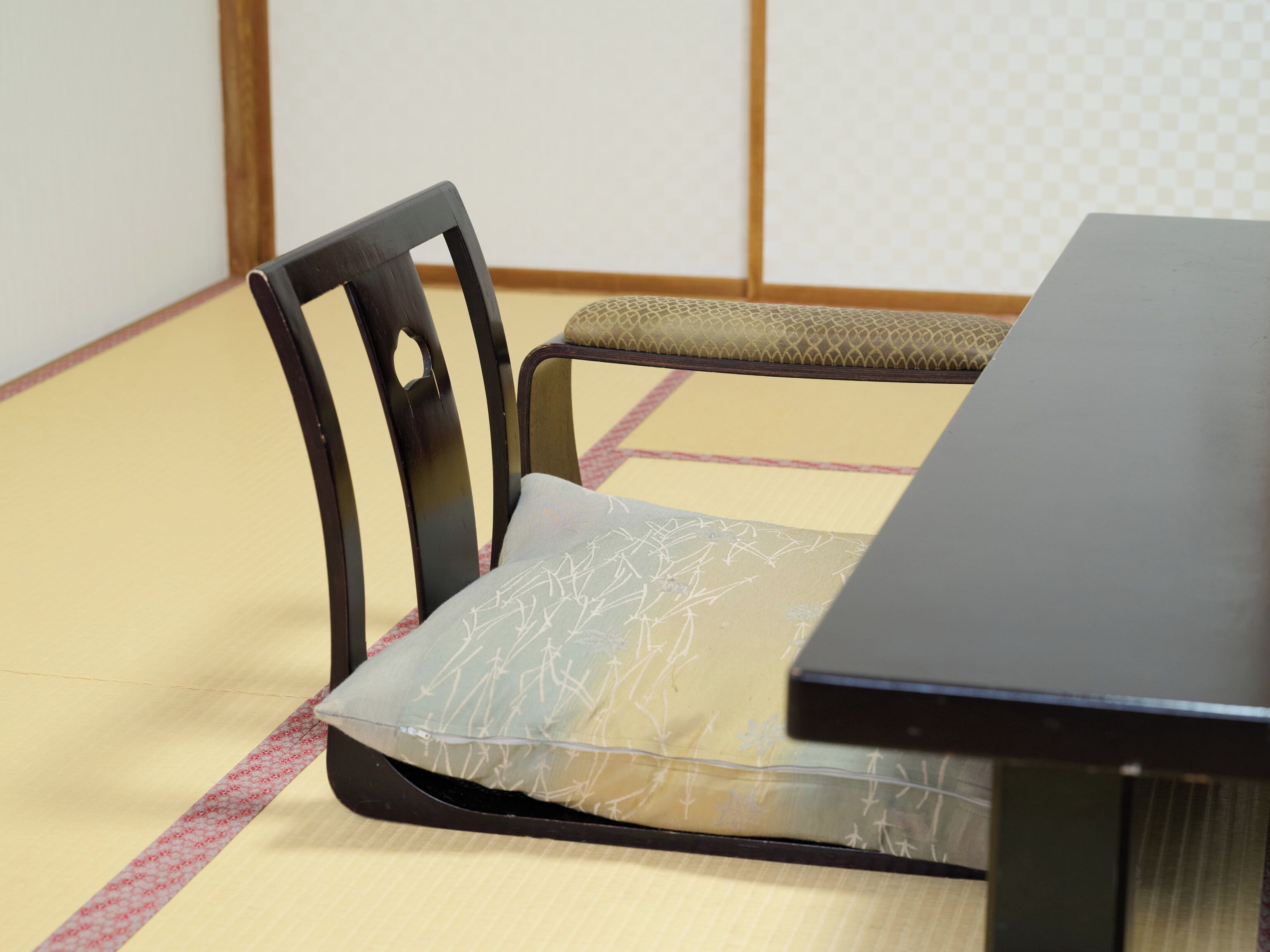 Un suelo de esteras de tatami con una mesita baja y una silla con cojín.