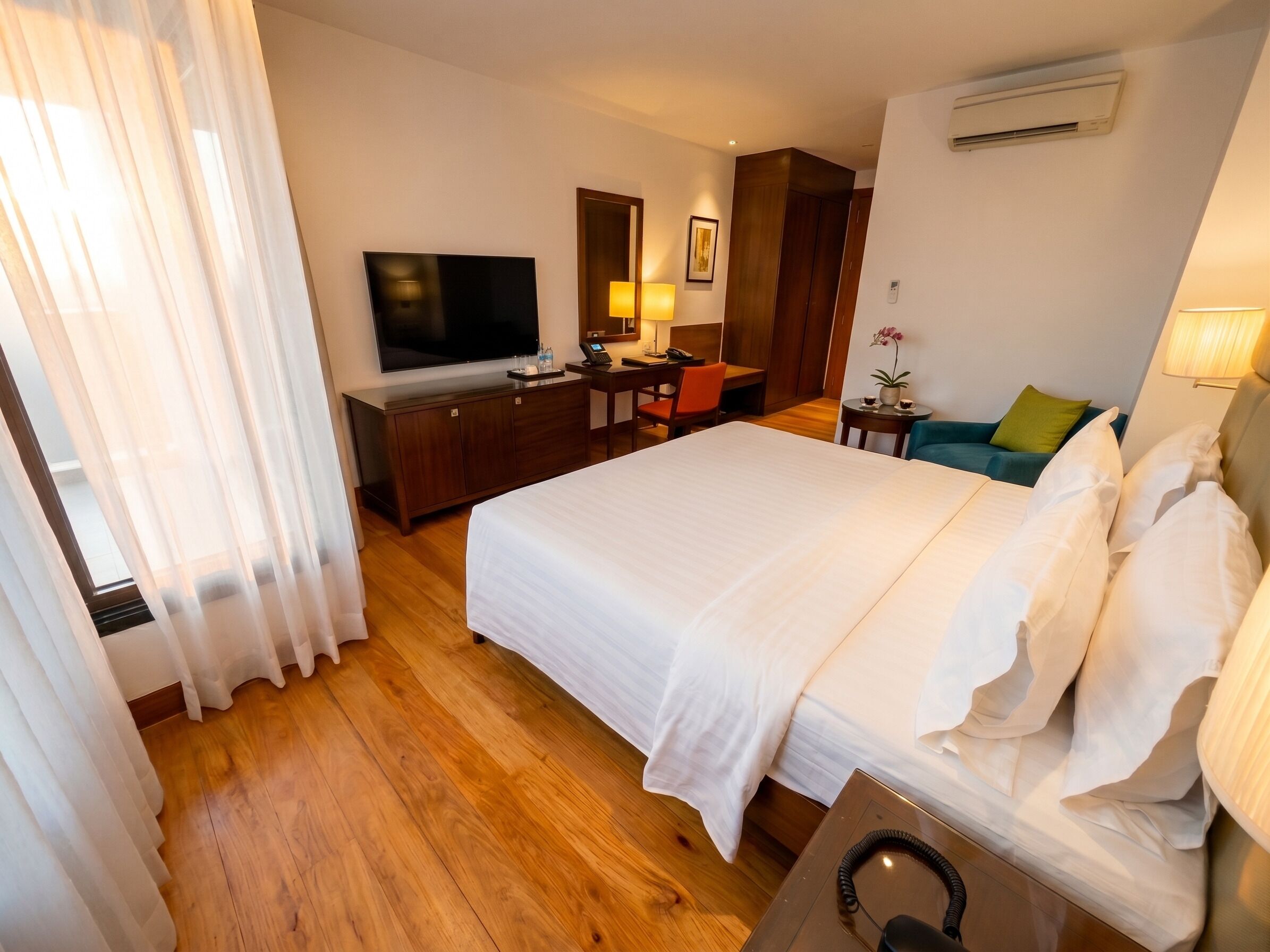 Une chambre d’hôtel avec un lit, un bureau, une télévision et une petite table avec une lampe.