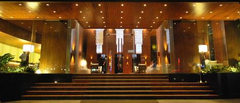 A hotel entrance with a wooden facade, steps leading up to the doors, and a glass entrance.