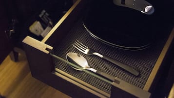A drawer with a black placemat, a spoon, a fork, and a knife.