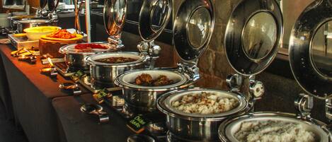 A buffet line with various food items in metal serving dishes.