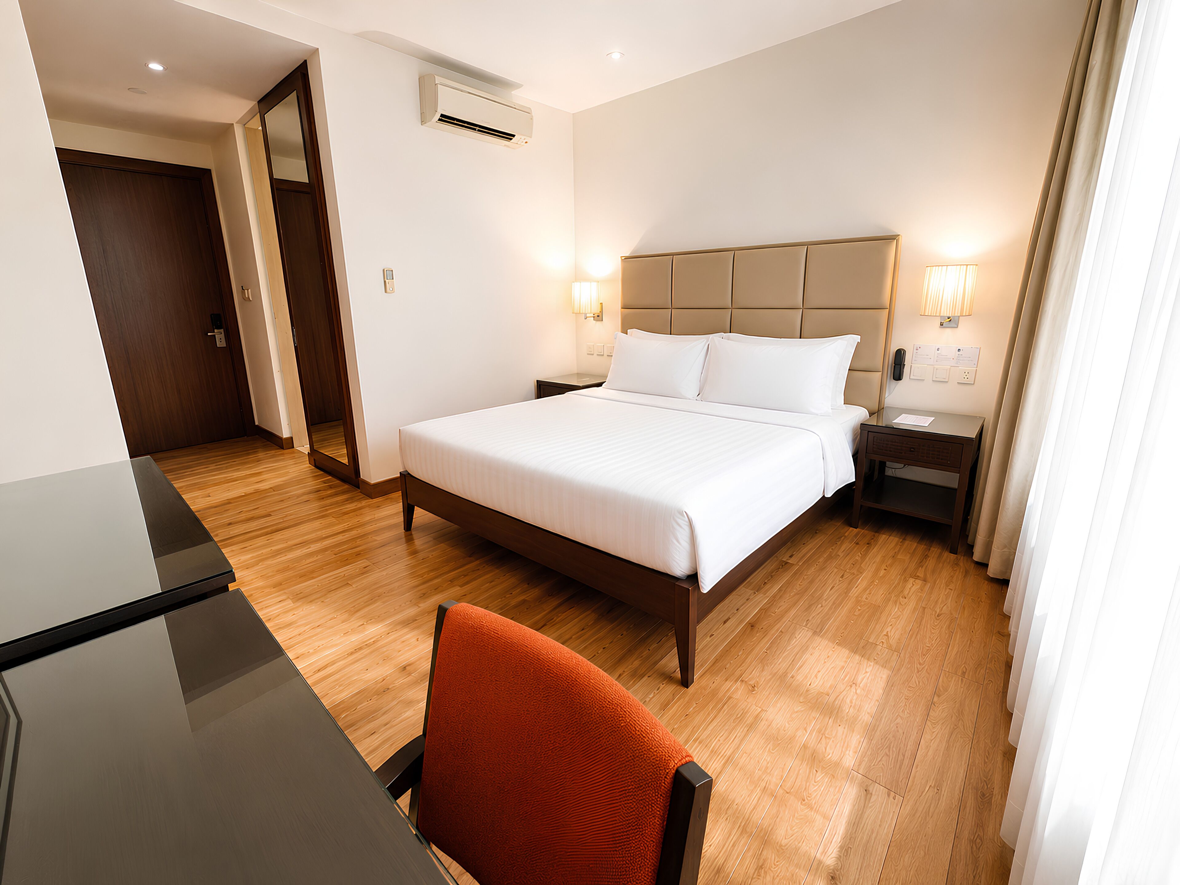 Una habitación de hotel con cama, mesita de noche, lámpara y una silla.