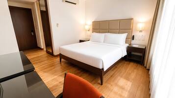 Una habitación de hotel con cama, mesita de noche, lámpara y una silla.